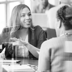 Black and white photo of a female banker talking to a client.